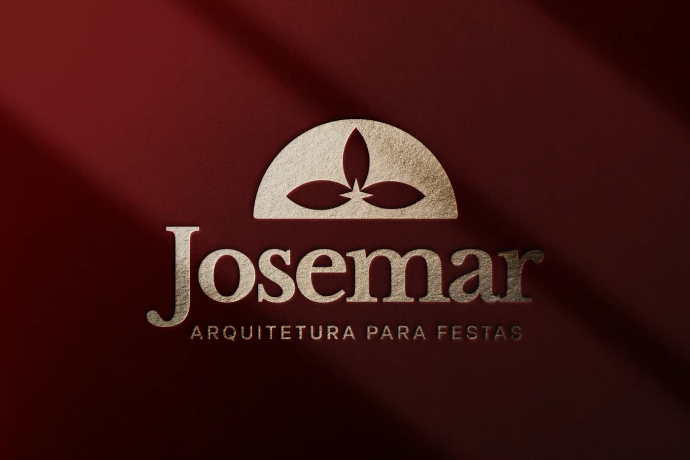 Logotipo Josemar em relevo dourado sobre papel vermelho escuro