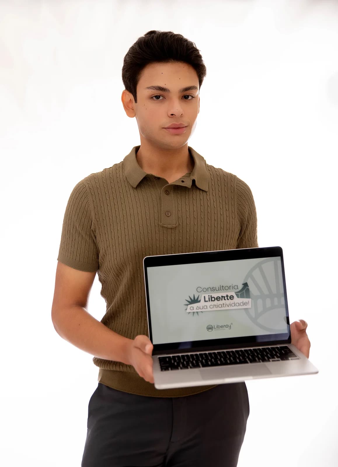 Jovem de polo segurando um notebook aberto com a peça da Consultoria Liberte a Sua Criatividade na tela
