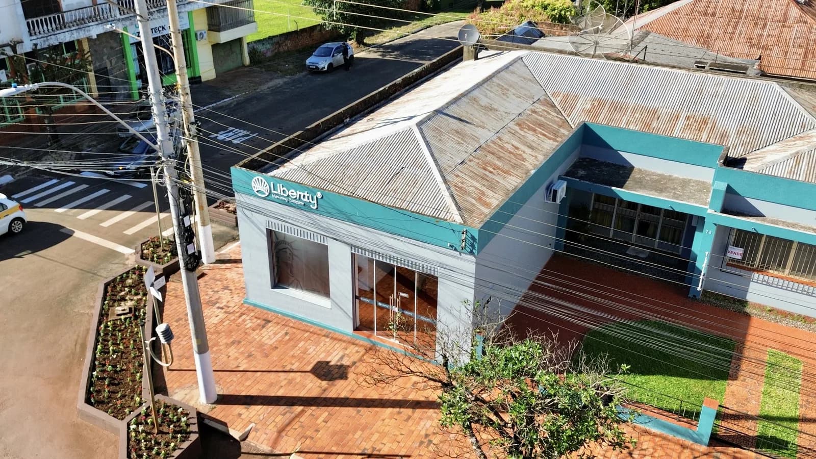 Vista aérea da fachada azul e branca do escritório da Liberty, na esquina, com o letreiro da marca sobre a vitrine
